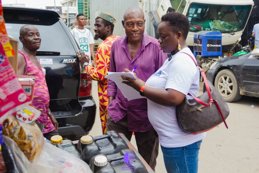 A Foundation volunteer talking with traders beside a parked car and noting their responses