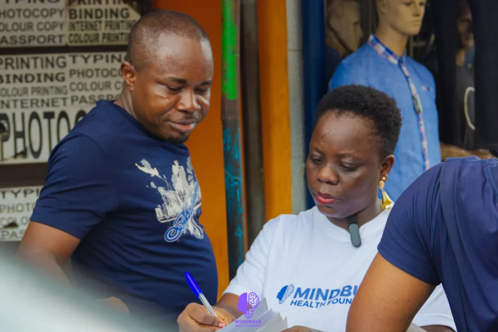 A Foundation volunteer filling in a short questionnaire with a man outside a print shop
